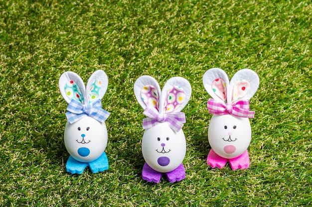 Lapins à la main mignons multicolores d'oeufs sur l'herbe verte