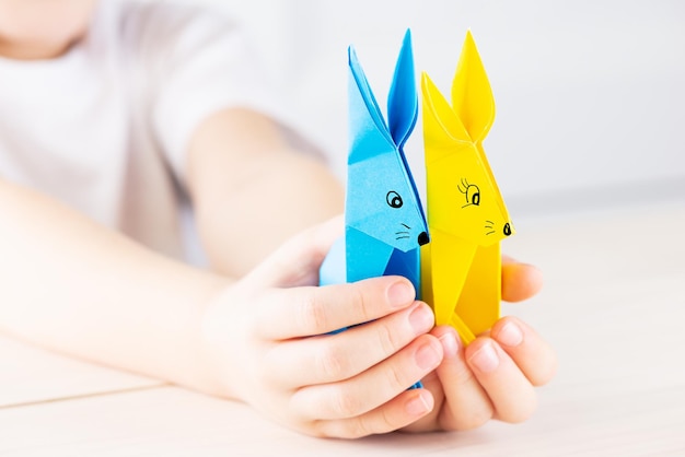 Lapins en papier entre les mains d'un enfant sur fond clair