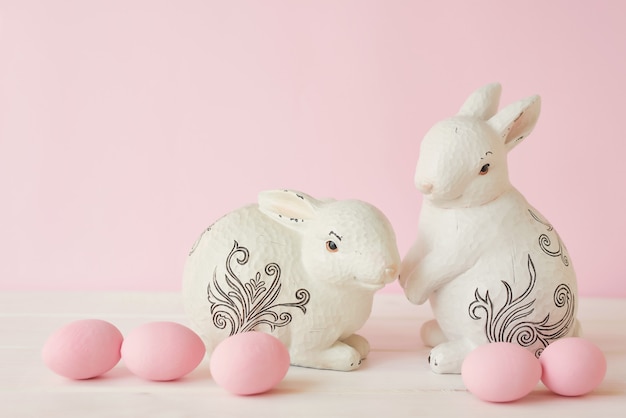 Lapins de Pâques avec des oeufs et une guirlande peints en rose