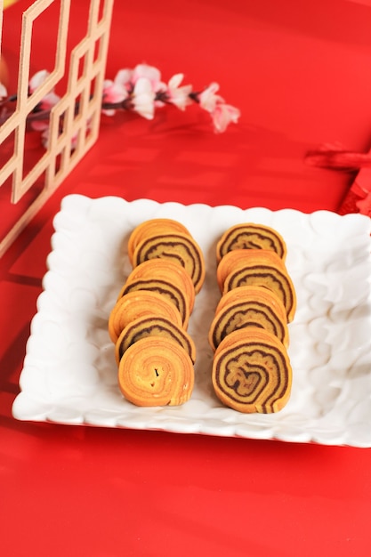 Lapis legit Roll Cake ou gâteau indonésien à mille couches dans une assiette blanche sur fond rouge. Ce gâteau servi sur le concept de célébration du nouvel an chinois (Imlek)