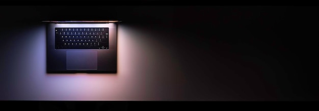 Laptop avec un écran brillant sur une table dans l'espace de copie de vue supérieure sombre