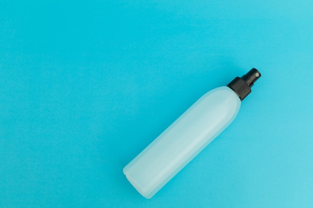 Laque pour cheveux en bouteille en plastique bleu sur fond bleu monochrome