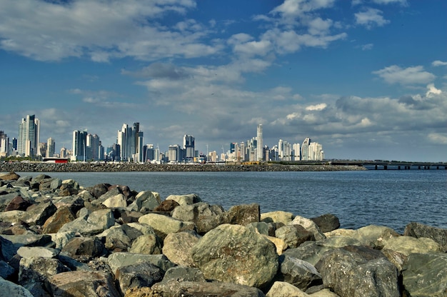 Large panorama des gratte-ciel et de la mer de Panama City vu de la côte de Casco Viejo avec des rochers au premier plan