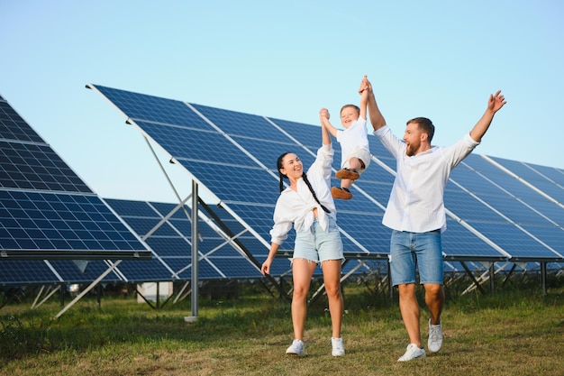 Un large plan d'une famille heureuse debout ensemble et souriant à la caméra avec un grand panneau solaire en arrière-plan