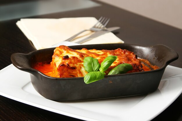 Lasagne bolognaise avec fourchette en argent sur la table en bois