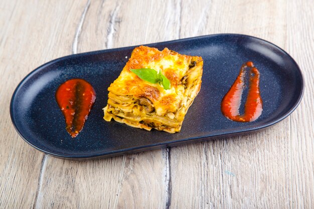 lasagne italienne à la sauce tomate sur une plaque noire et vue de dessus de fond en bois