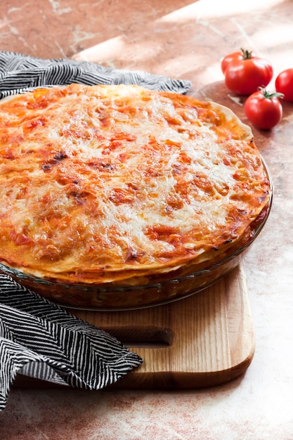 Lasagnes cuites au four dans un plat de cuisson en verre rond sur planche de bois