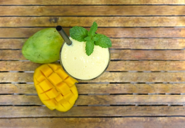 Lassi à la mangue avec des tranches de mangue fraîche sur la vue de dessus de fond en bois