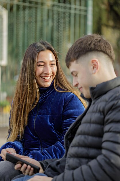 Latina girl smiling assis sur un banc de plaza avec son petit ami