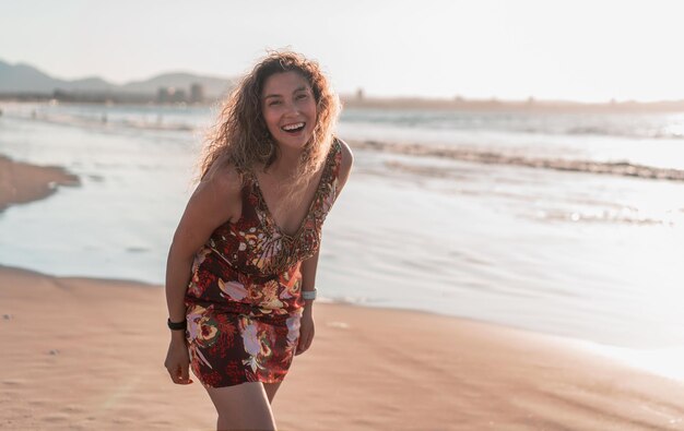 Latine jeune femme souriante heureuse sur la plage en regardant la caméra