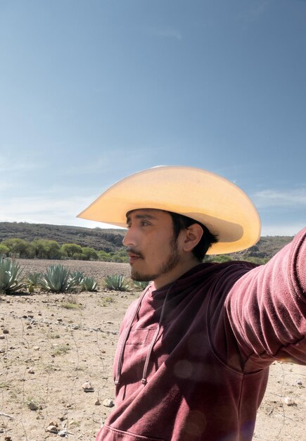 Un Latino mexicain avec un chapeau travaillant dans le champ entouré d'agaves de pulque et de tequila