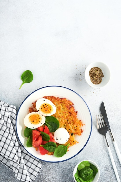 Latkes de pommes de terre au petit-déjeuner avec salade d'épinards à la crème sure, tomates et œufs durs sur fond clair Nourriture délicieuse pour le petit-déjeuner Vue de dessus