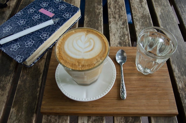 Latte art café chaud avec carnet de notes et appareil photo du blogueur de voyageurs sur une table en bois dans un café et un restaurant à Tak Thaïlande
