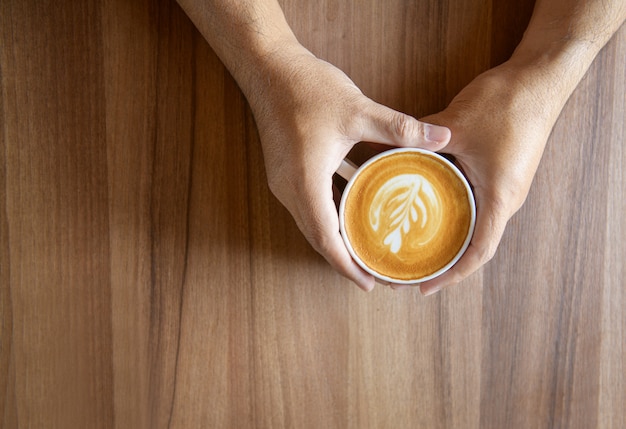 Latte art.Homme mains tenant une tasse de café