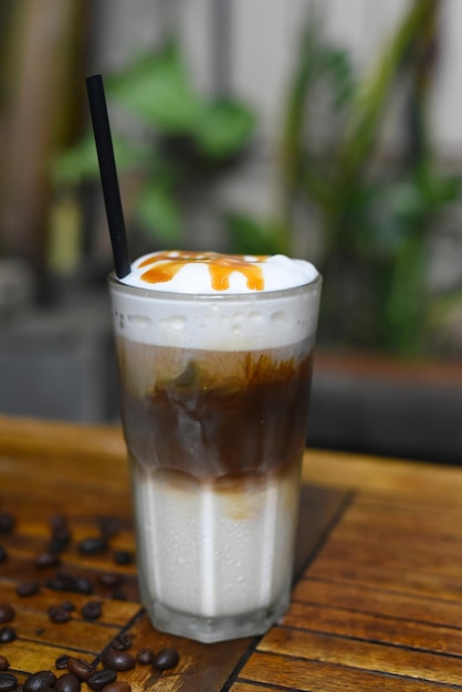 Latte au caramel glacé avec des grains de café sur une table en bois