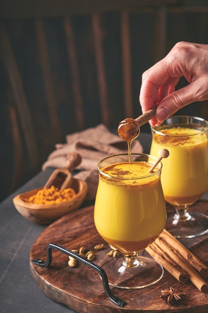 Latte au lait doré au curcuma avec des bâtons de cannelle et du miel. Boisson ayurvédique saine. Boisson de désintoxication naturelle asiatique à la mode avec des épices pour les végétaliens. Espace de copie.