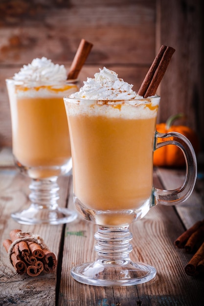 Latte aux épices à la citrouille avec crème fouettée sur table en bois