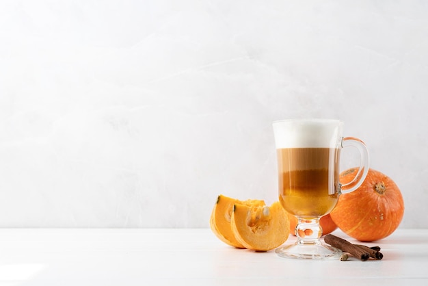 Latte aux épices à la citrouille dans une tasse en verre à la cannelle