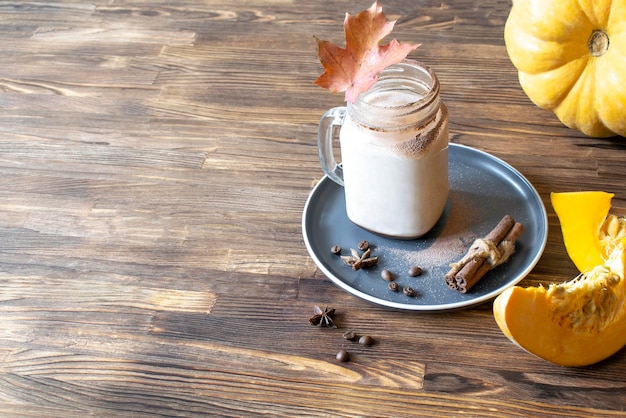 Latte café cacao avec lait citrouille cannelle épice dans une tasse de tasse transparente en verre sur fond de bois recette de boisson traditionnelle d'automne chaude et chaude par temps froid