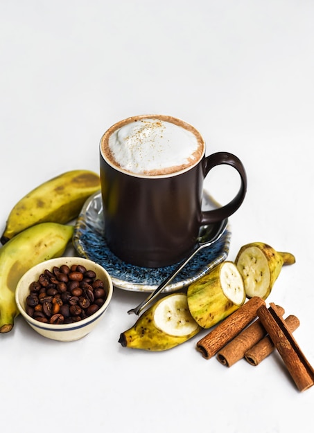 Latte chaud à la banane avec cannelle et banane fraîche sur tableau blanc