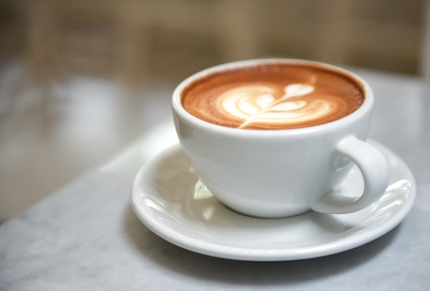 Latte close-up dans une tasse blanche sur la table avec un arrière-plan flou.