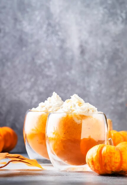 Latte épicé à la citrouille ou café dans une double tasse en verre sur une table grise Boisson chaude d'automne ou d'hiver dans une table de fête