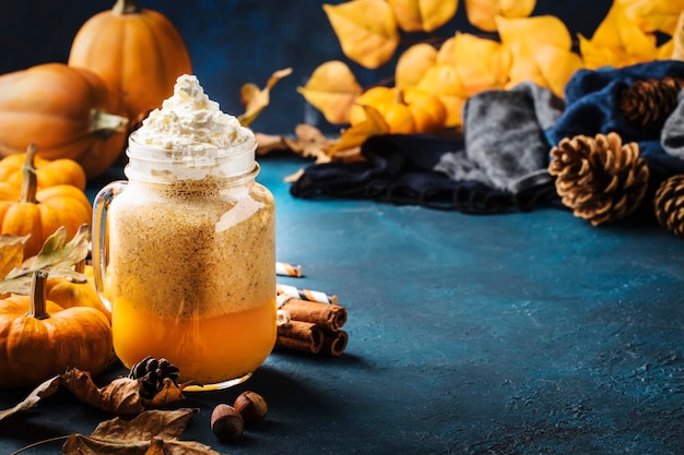 Latte épicé à la citrouille ou café dans une tasse en verre sur une table bleue Boisson chaude d'automne ou d'hiver dans un décor de table naturel festif