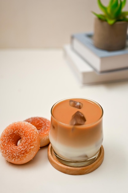 Latte glacé un verre de latte glacé avec de délicieux beignets sur un bureau blanc