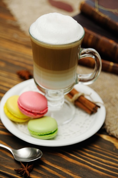 Latte et macarons sur fond de bois sur fond de vieux livres et toile de jute