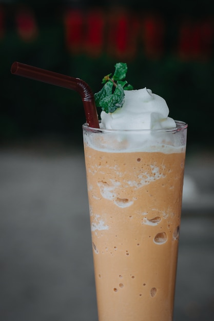 Latte mélangé avec de la crème fouettée, un tracé de détourage. Mélangeur à café glacé dans un verre.