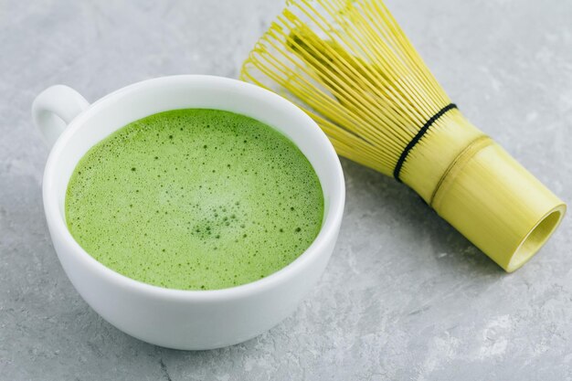 Latte de thé vert matcha japonais dans une tasse blanche sur fond de pierre grise