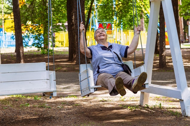 Laughing senior woman sitting on swing with copy space s'amusant et profitant de la retraite