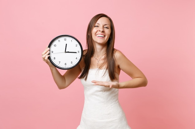 Laughing woman in white dress pointant la main sur le réveil rond