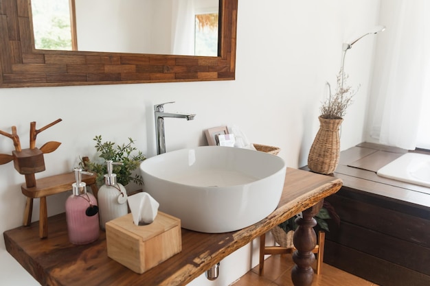 Le lavabo et le robinet de style moderne sont posés sur une table en bois et disposent d'une baignoire près de la fenêtre La salle de bains moderne est dotée d'un beau mobilier en bois orné Il y avait une lumière près de la fenêtre le matin