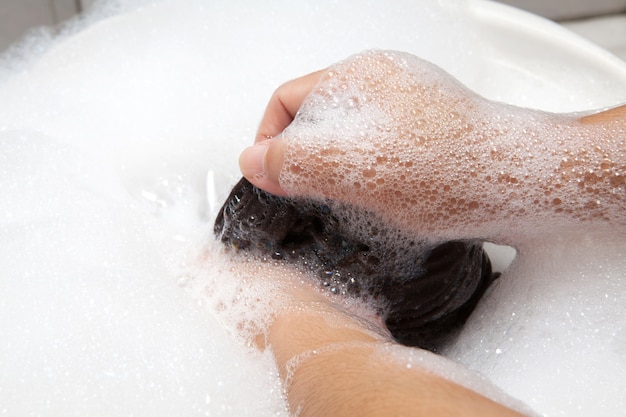 Lavage des mains avec des bulles sur le bassin blanc.