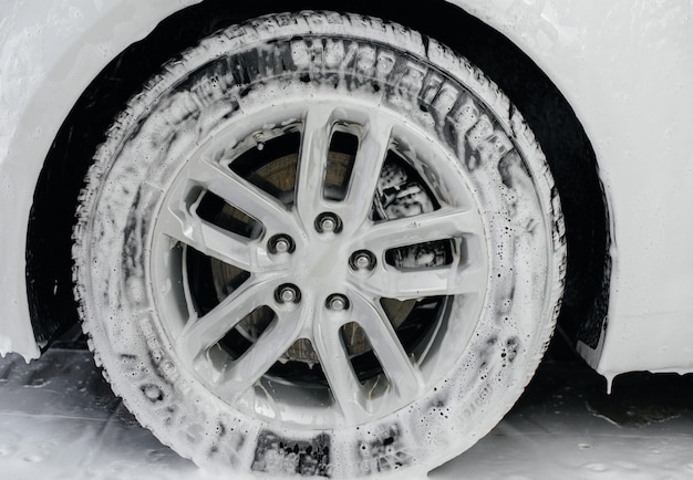 Lavage moderne des roues de voiture avec mousse et haute pression d'eau. Lave-Auto.