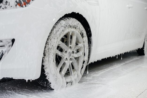 Lavage moderne des roues de voiture avec mousse et haute pression d'eau. Lave-Auto.