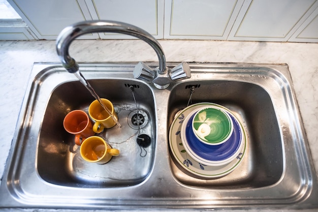 Lavage des tasses sales dans l'évier de la cuisine