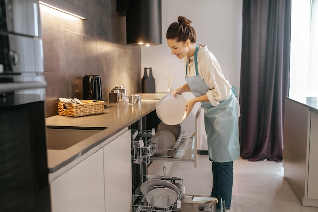 Lavage de vaisselle. Femme debout près du lave-vaisselle et sortant les assiettes