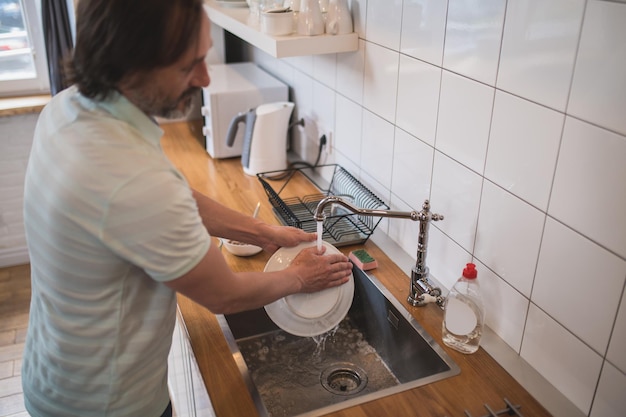 Lavage de vaisselle. Homme faisant la vaisselle dans la cuisine