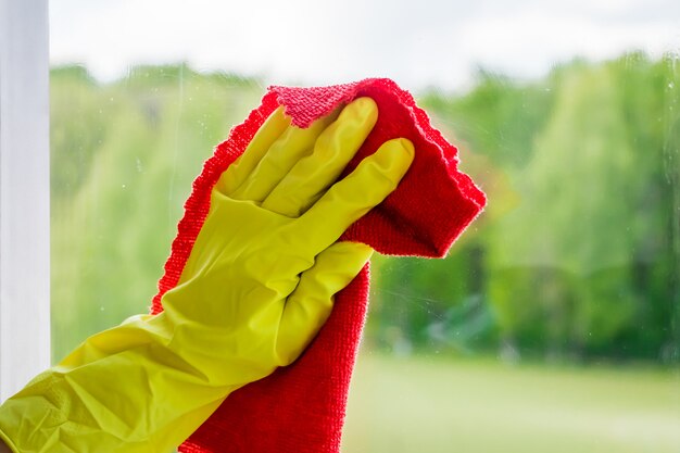 Lavage de vitres et nettoyage à domicile. Femme de ménage en gants lave et essuie le verre sale.