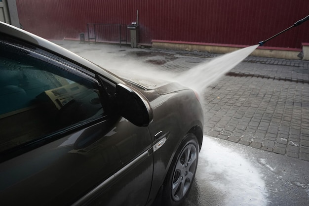 Lavage de voiture Nettoyage d'une voiture avec de l'eau à haute pression dans un lave-auto