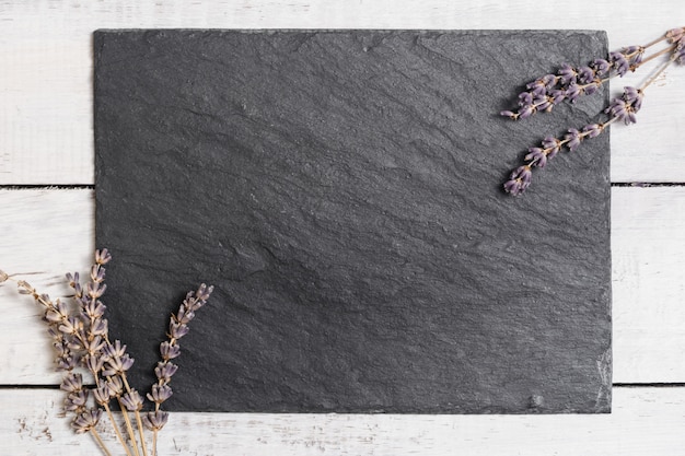 Lavande sur une planche de graphite noir sur une table en bois rustique blanche.