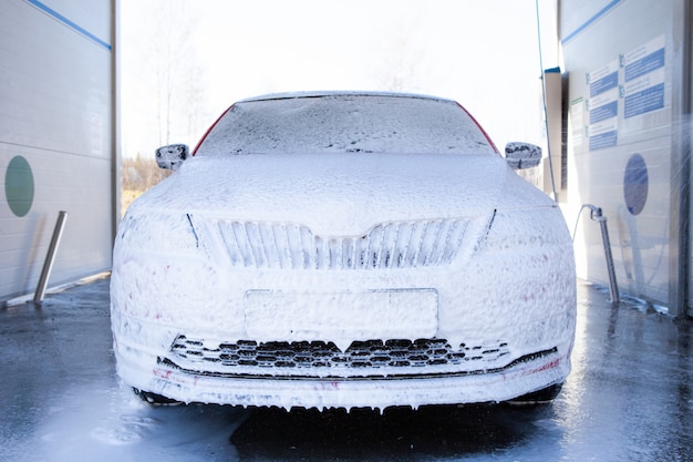 Lave-auto avec du savon et de l'eau à haute pression. La machine est complètement du savon