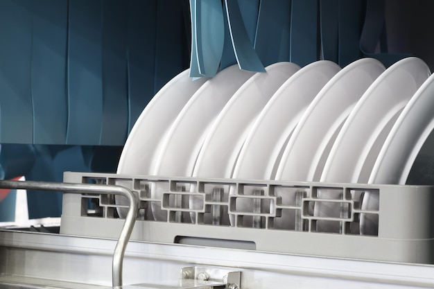 Photo le lave-vaisselle automatique avec des plats propres blancs dans le panier pour le restaurant contexte industriel d'affaires