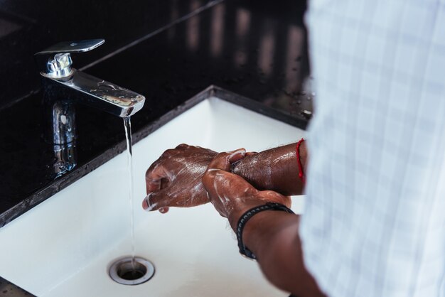 Photo laver les mains de l'homme noir se frottant avec du savon et de l'eau dans les éviers