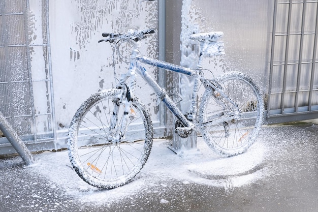 Laver un vélo avec un jet de mousse dans une station de lavage Le vélo est recouvert de mousse Entretien des vélos en libre-service
