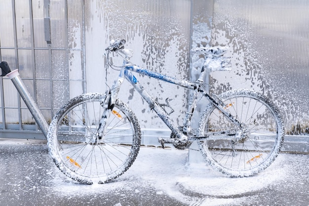 Laver un vélo avec un jet de mousse dans une station de lavage Le vélo est recouvert de mousse Entretien des vélos en libre-service