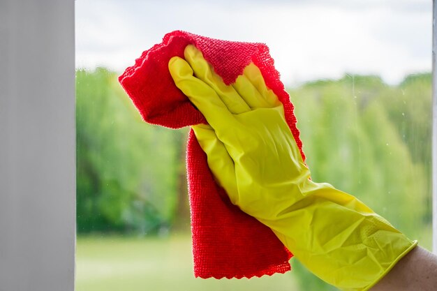 Laver les vitres. Jeune femme en gants de caoutchouc jaune essuie le verre. Notion de ménage.