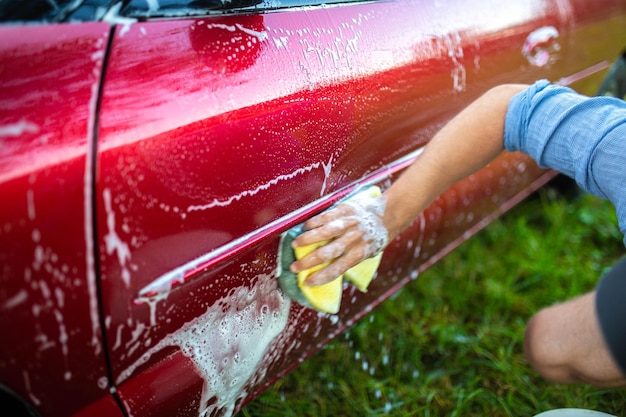 laver la voiture à la main avec une éponge et du shampoing la voiture est rouge